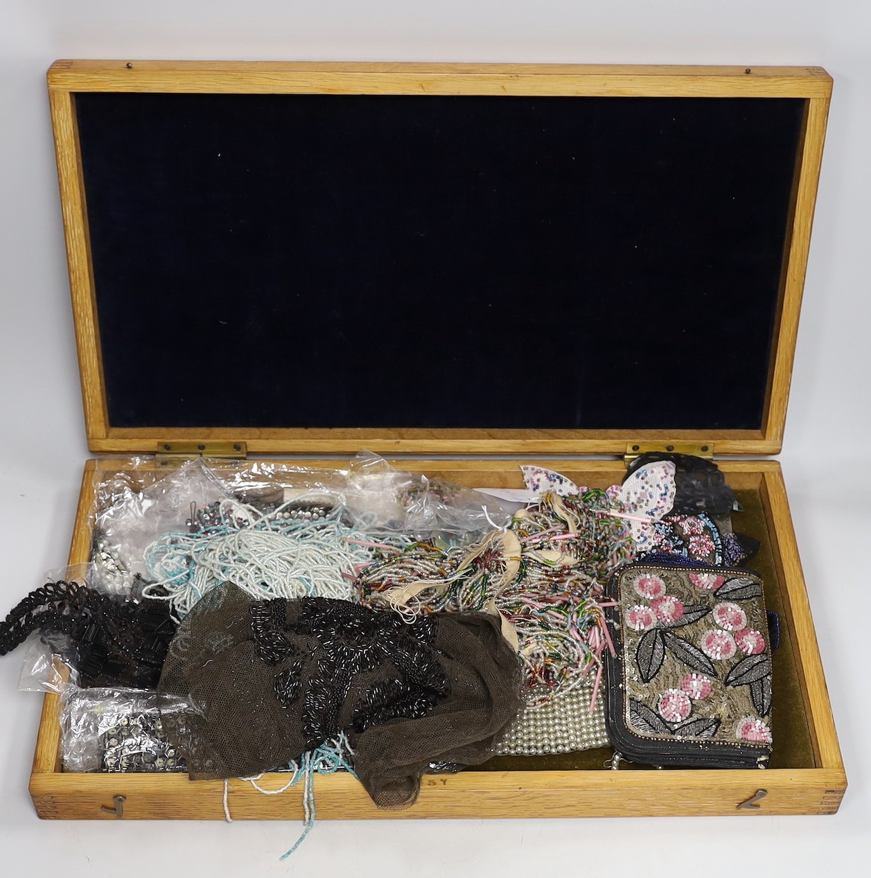 An oak box containing a mixed collection of decorative jet and coloured beaded trimmings, inserts, panels and fringing etc.